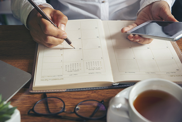 Female hand of planner writing daily appointment.