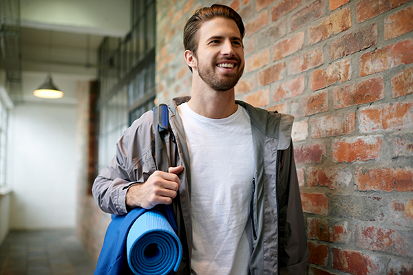 Shot of a young man carrying his gym bag down a hallway