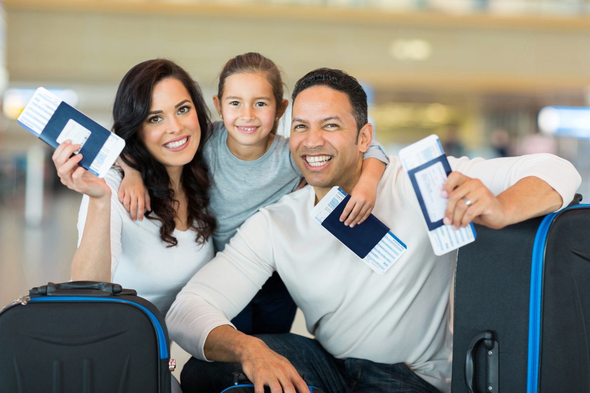 a family smiling holding their passports and plane tickets at the airport
